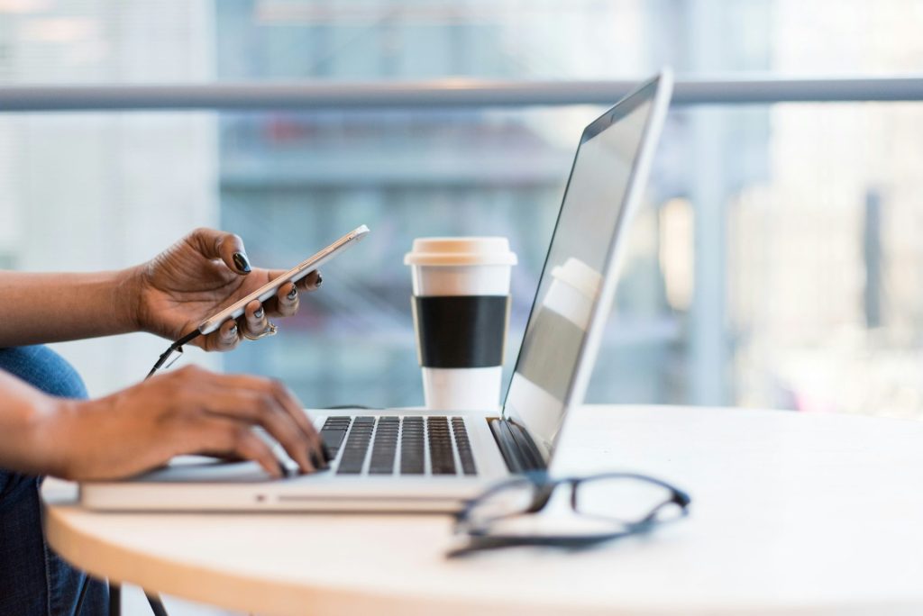 Person, die Smartphone und MacBook verwendet