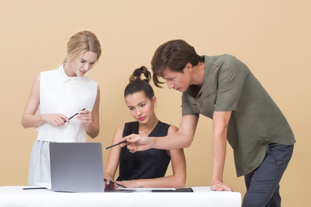 Mann unterrichtet Frau und zeigt auf grauen Laptop